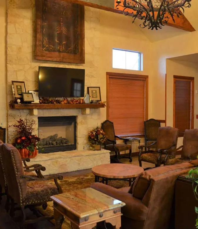 The waiting room, with a stone fireplace, leather armchairs and wood shutters.